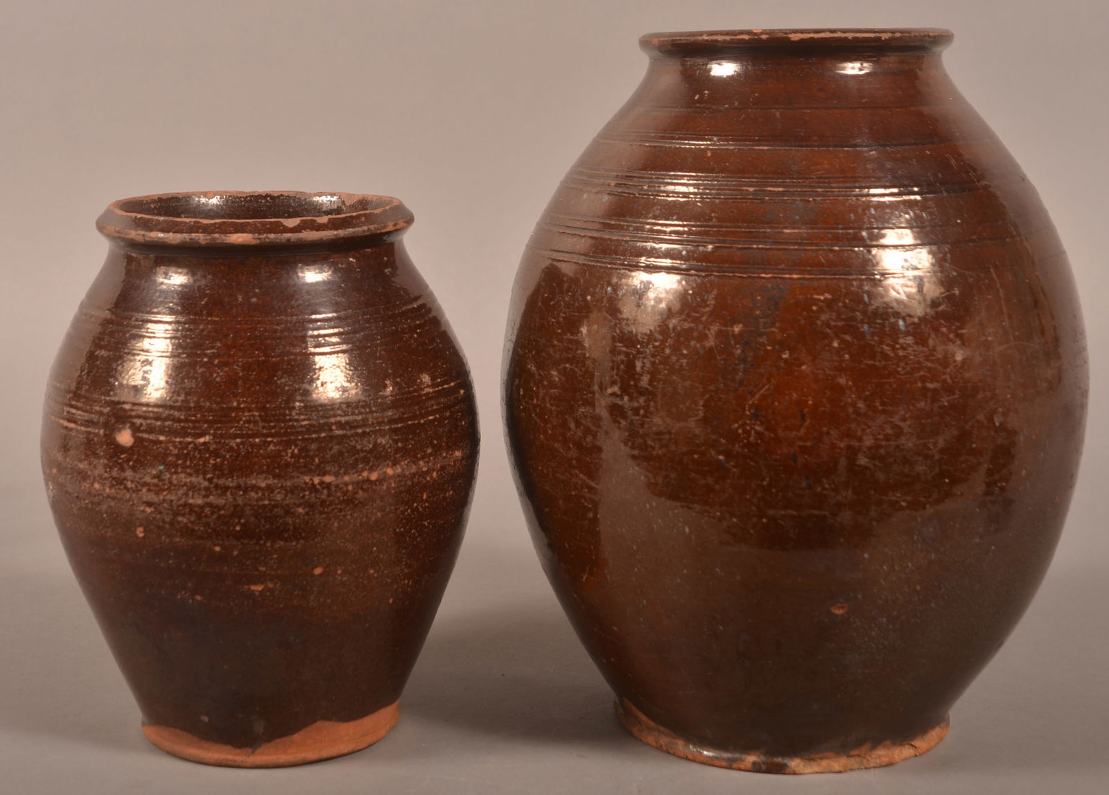Two American 19th C. Redware Storage Jars.: Two American 19th Century Manganese Glazed Redware Storage Jars. Molded rims and bulbous bodies with incised ring decoration. 8-1/4"h. and 11"h.