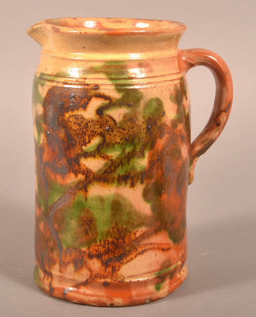 Shenandoah Valley Glazed Redware Pitcher.: Shenandoah Valley Polychrome Mottled Glaze Redware Pottery Pitcher. Attributed to J. Eberly & Co. Strasburg, VA, ca. 1885-1899. Flared rim with shaped spout, incised bands, beveled loop handle, and mo