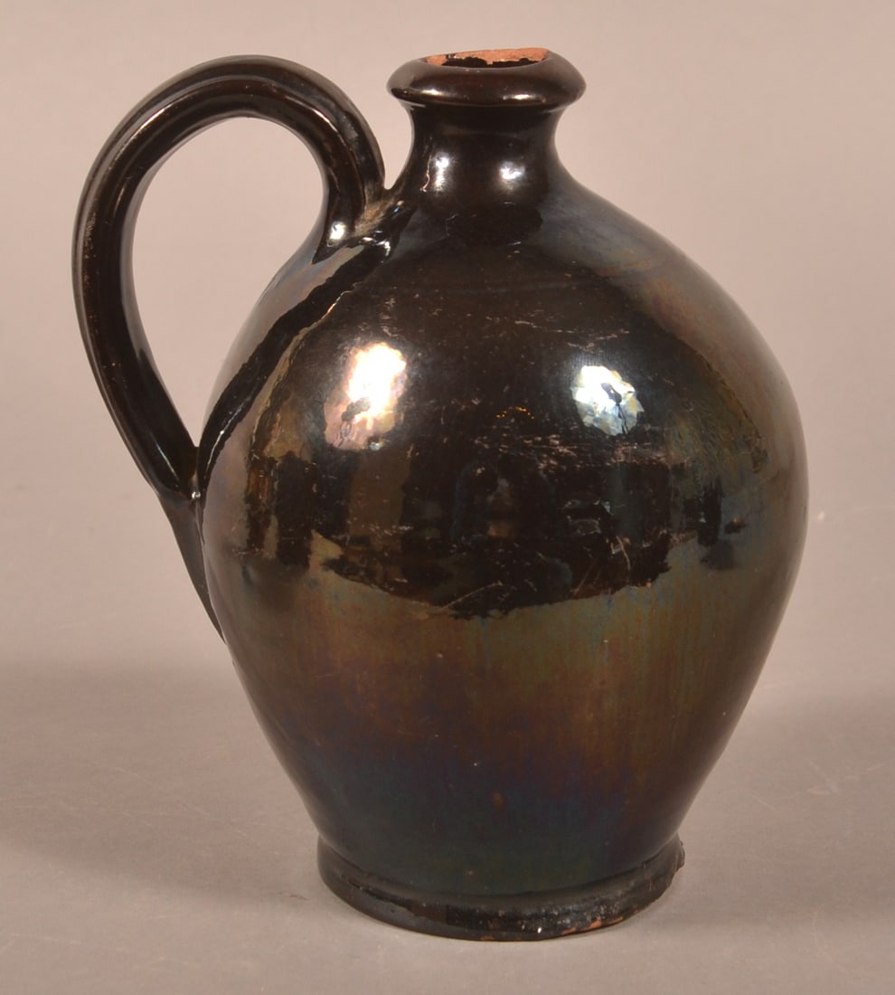 Dark Manganese Glazed 19th Century Redware Jug.: Dark Manganese Glazed 19th Century Redware Jug. Semi-round spout, applied ribbed loop handle, and tooled shoulder on bulbous body. 7-1/4"h.