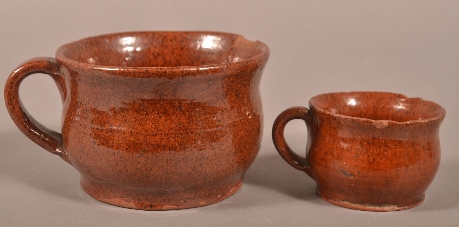 Two Pennsylvania 19th C. Glazed Redware Mugs.: Two Pennsylvania 19th Century Glazed Redware Mugs. Bulbous form with flared rims and applied strap handles. 2"h. and 3"h.