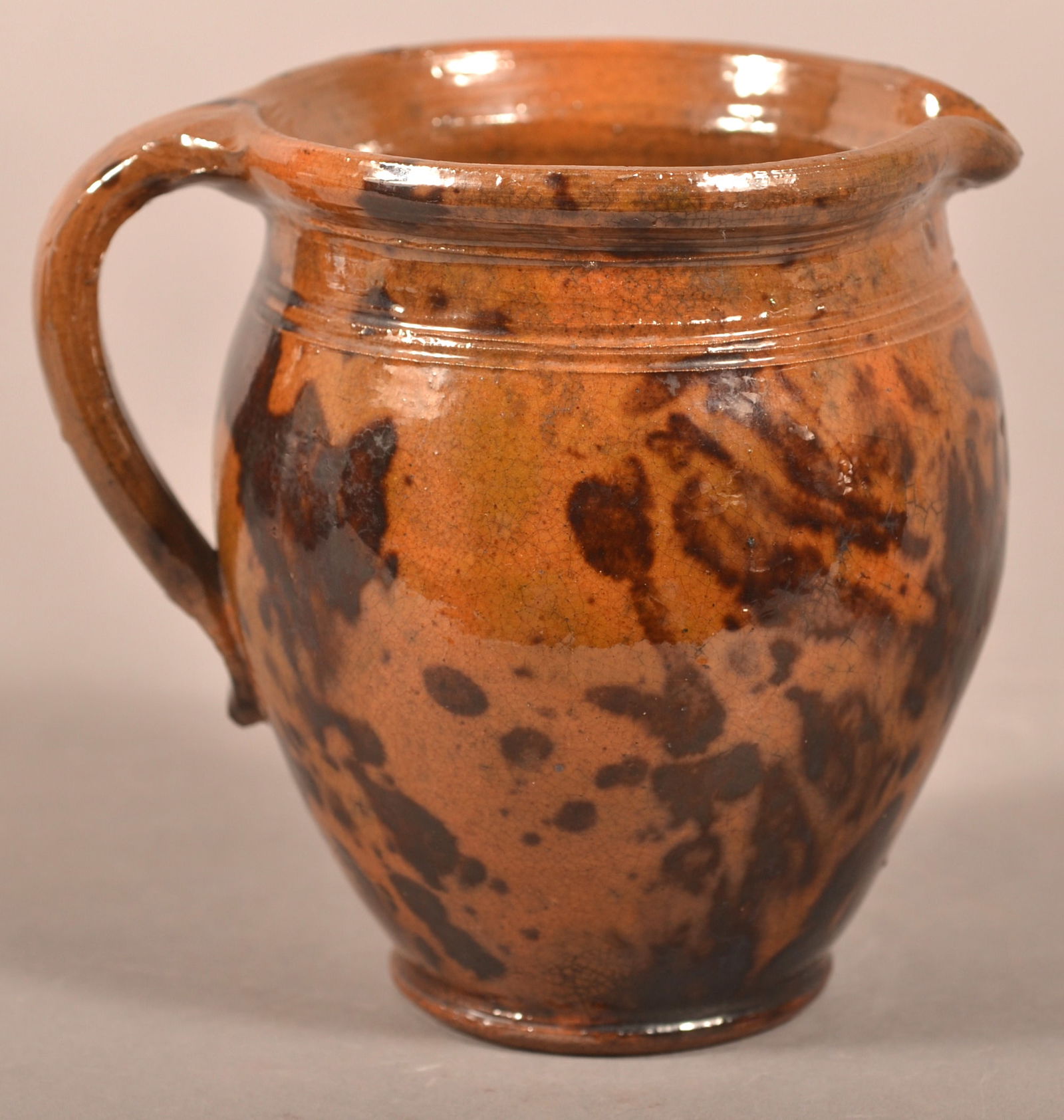 PA 19th C. Mottled Glaze Redware Cream Pitcher.: Pennsylvania 19th Century Mottled Glaze Redware Cream Pitcher. Bulbous form with pinched spout and loop handle. 4-1/2"h.