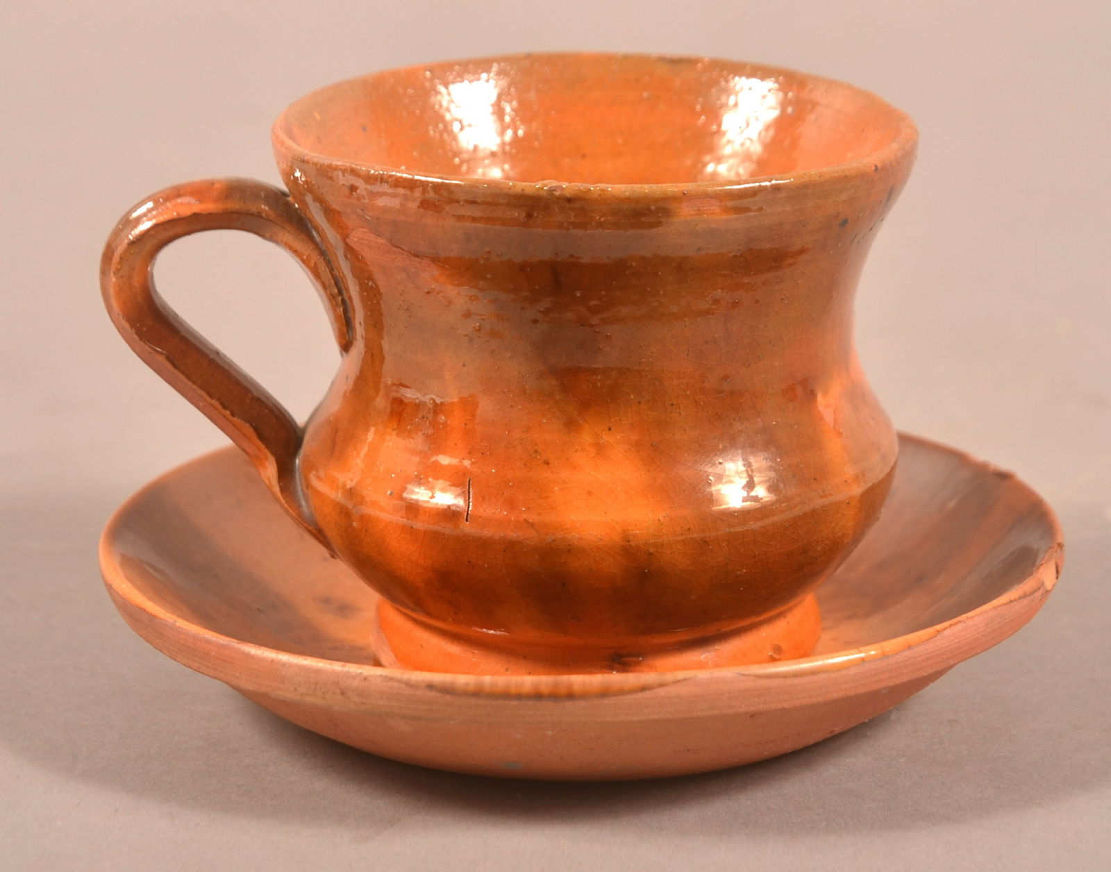 PA 19th C. Mottled Glaze Redware Cup and Saucer.: Pennsylvania 19th Century Mottled Glaze Redware Cup and Saucer. Cup with flared rim, bulbous body and applied loop handle. Rare form to see cup and saucer in redware pottery. Cup, 2-3/4"h., saucer, 5"