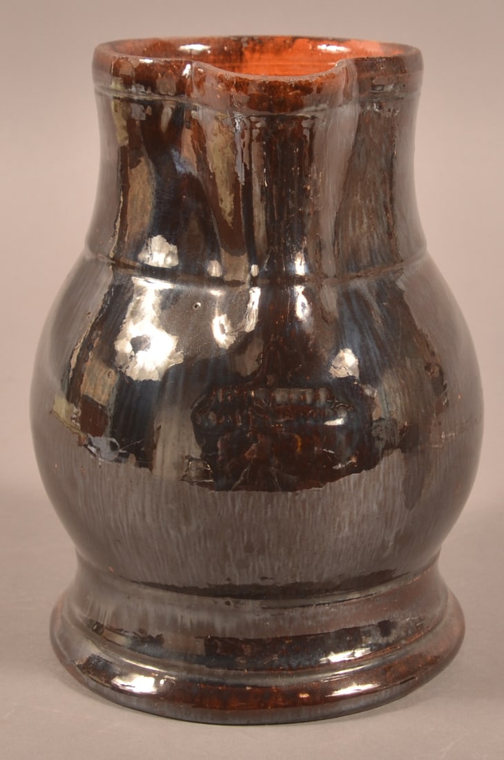 John Bell, Waynesboro, PA Redware Milk Pitcher.: John Bell, Waynesboro, PA Manganese Glazed Redware Milk Pitcher. Pinched spout with molded rim, applied shaped handle, bulbous body, and molded base. 7-1/2"h.