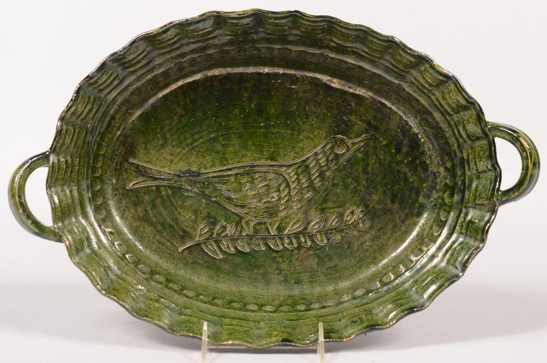 Green Oval Earthenware Handled Baking Dish. Pie crust r: Green Oval Earthenware Handled Baking Dish. Pie crust rim with finger tip impressed border around an incised image of a bird on center. Applied loop handles on each end. Curved bottom. Rim decoration