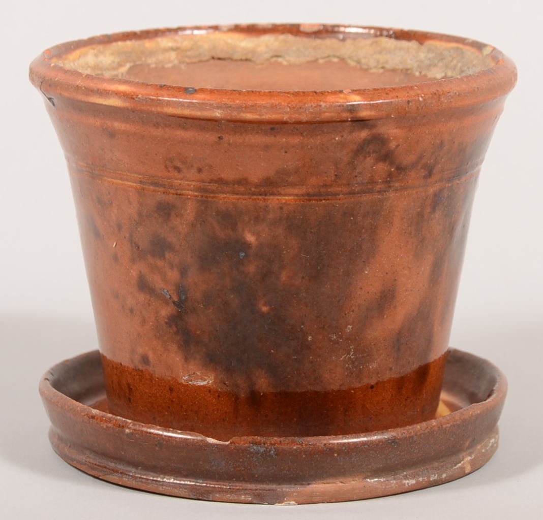 Redware Flower Pot with Attached Saucer. Manganese and : Redware Flower Pot with Attached Saucer. Manganese and yellow underglaze decoration. Drain hole in pot to saucer. 4 1/4"h. X 5 1/8"dia. Condition: Two chip off inside of saucer rim.