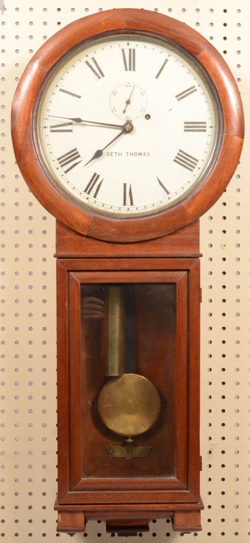 Seth Thomas Eight Day Half Hour Strike Wall Clock. Waln: Seth Thomas Eight Day Half Hour Strike Wall Clock. Walnut veneer case with glazed round dial case on a glazed and bracketed rectangular lower pendulum case. Weight, pendulum and winder included. 36 1/