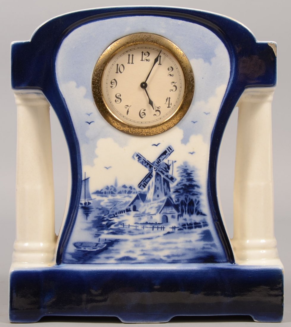 German Marked Delft Style Ceramic Shelf Clock. White ch: German Marked Delft Style Ceramic Shelf Clock. White china case with side columns having a cobalt transfer of an old windmill at stream side with boats. Blue footed base. Brass bezel. Marked on back.