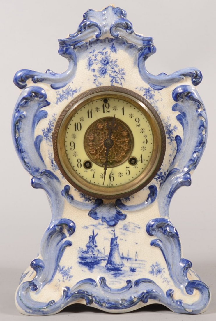 Blue Delft Style China Cased Shelf Clock. Paper label, : Blue Delft Style China Cased Shelf Clock. Paper label, verso identifies the maker as "Oakley." Relief foliate designs on face of case with painted floral bouquets and vignettes of Dutch boats and wind