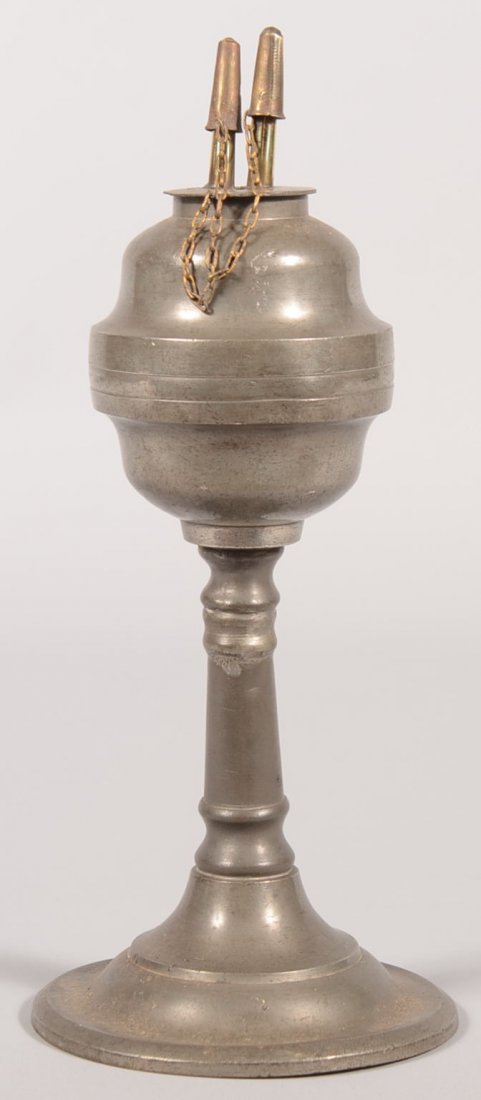 Pewter Pedestal Fluid Lamp. Raised molded base, columna: Pewter Pedestal Fluid Lamp. Raised molded base, columnar standard and matched ogee font with brass wick holders and caps on chain. 10 1/4"h. Condition: Good with use wear.