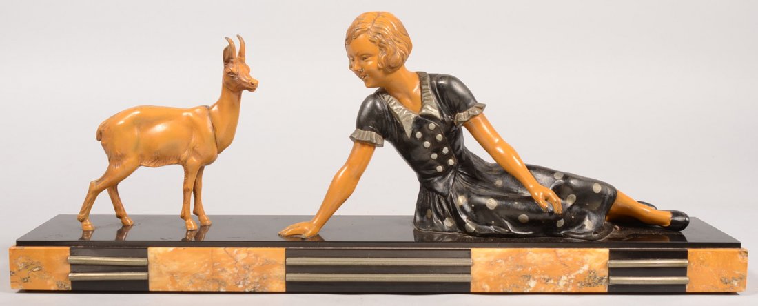 Art Deco Statues on Marble Base. A young woman: Art Deco Metal Statues on Marble Base. A young woman in a silver polka dotted black dress reclining on her side and conversing with a small amber colored antelope on a black marble veneered base with