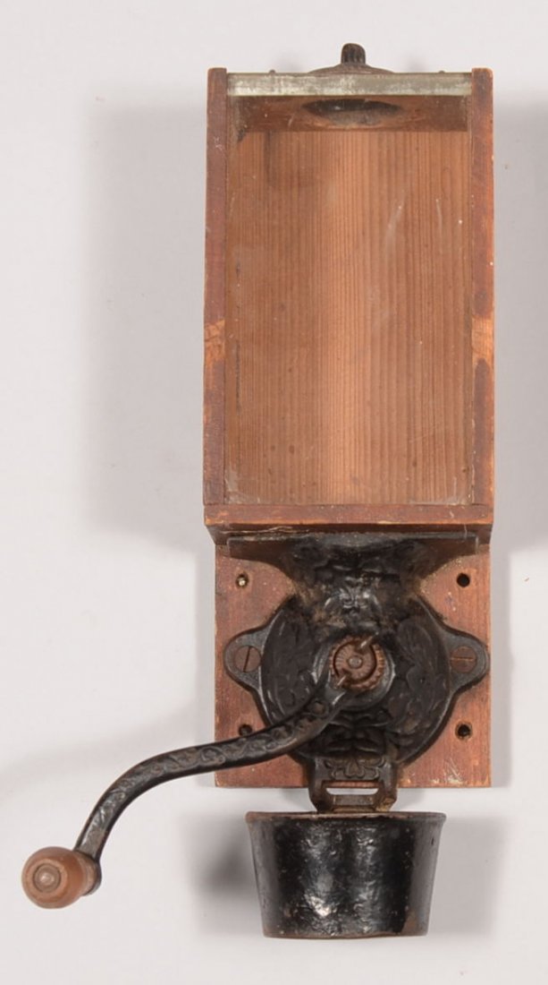 Wall Mounted Iron and Wood Coffee Grinder. Cast iron de: Wall Mounted Iron and Wood Coffee Grinder. Cast iron device is mounted on a wood plank with a glass pane fronted wood box hopper having a cast iron cover. No maker's marks. 12"h. X 4 5/8"w. Condition:
