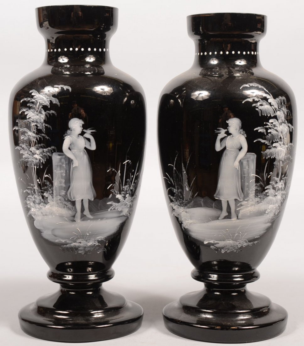Mary Gregory Decorated Black Glass Vases or Urns. Swell: Mary Gregory Decorated Black Glass Vases or Urns. Swelled body on a stepped raised foot, reduced neck and open mouth with gilt rim. Bodies decorated with facing images of a girl kissing a small bird o