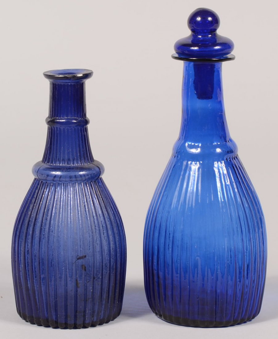 Two Cobalt Blue Mold Blown Toiletry Bottles. Both simil: Two Cobalt Blue Mold Blown Toiletry Bottles. Both similar with reeded bodies and neck ring. One having a blown flared mouth with smooth neck, a broken pontil and a blown stopper, 6 7/8"h. Along with a