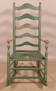 PA Late 18th Century Ladder-Back Rocking Chair.: Woven splint seat turnip finials, arched ladder-back, shaped arms and cheese cutter rockers. Old green paint. Seat height, 18-1/2" H, 46-1/2" H x 23" W overall.