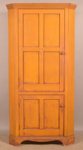 Diminutive Ohio Single-Part Corner Cupboard.: Softwood, mustard yellow over red paint. Double molded cornice, paneled blind doors and shaped bracket base. 74-1/2" H x 36" W x 20" D