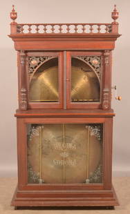 Regina Orchestral "Corona" Disc Changer Music Box.: Victorian mahogany case music box with twelve 27" discs. Bronze castings adorn the top of corners of the two front doors and are flanked by carved columns. Serial # 46382. 73" H x 39" W x 25" D