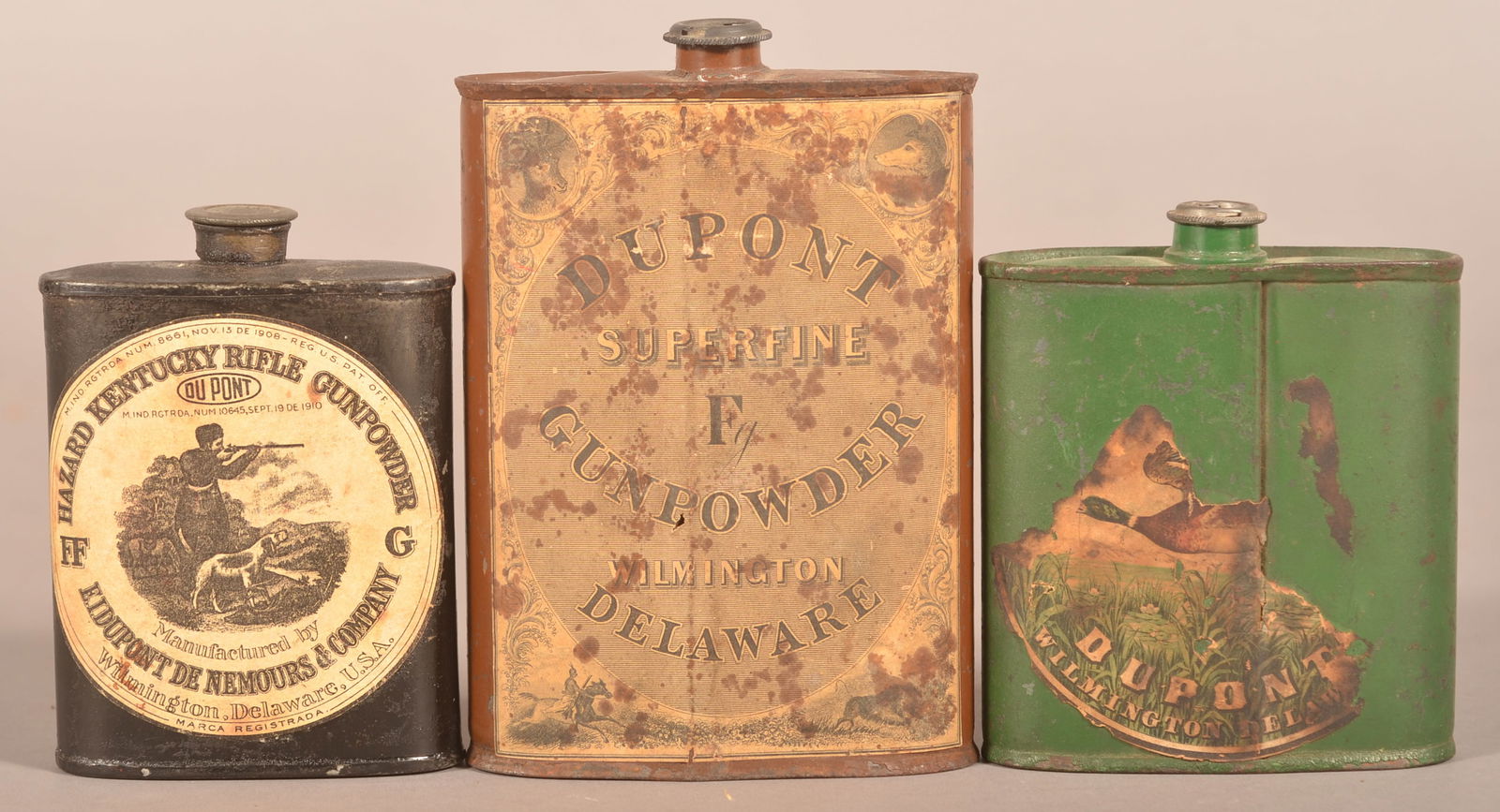 Three DuPont Kentucky Rifle Gunpowder Flasks.: Includes an early flask with remnant of paper label, black flask with paper label with hunting scene, and a larger single F gunpowder tin. Largest, 6" H x 4" W x 1-1/2" D