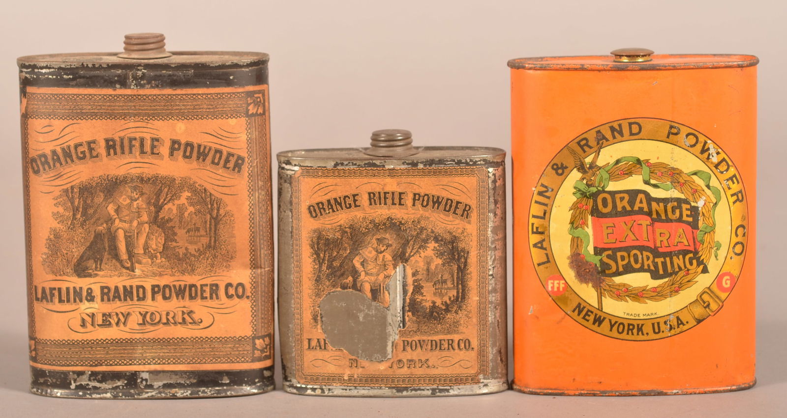 Three Laflin & Rand Powder Gunpowder Flasks.: Orange tin for Extra Sporting. The other two tins are different sizes for Rifle Powder. Largest flask, 5-1/2" H x 4" W x 1-1/2" D