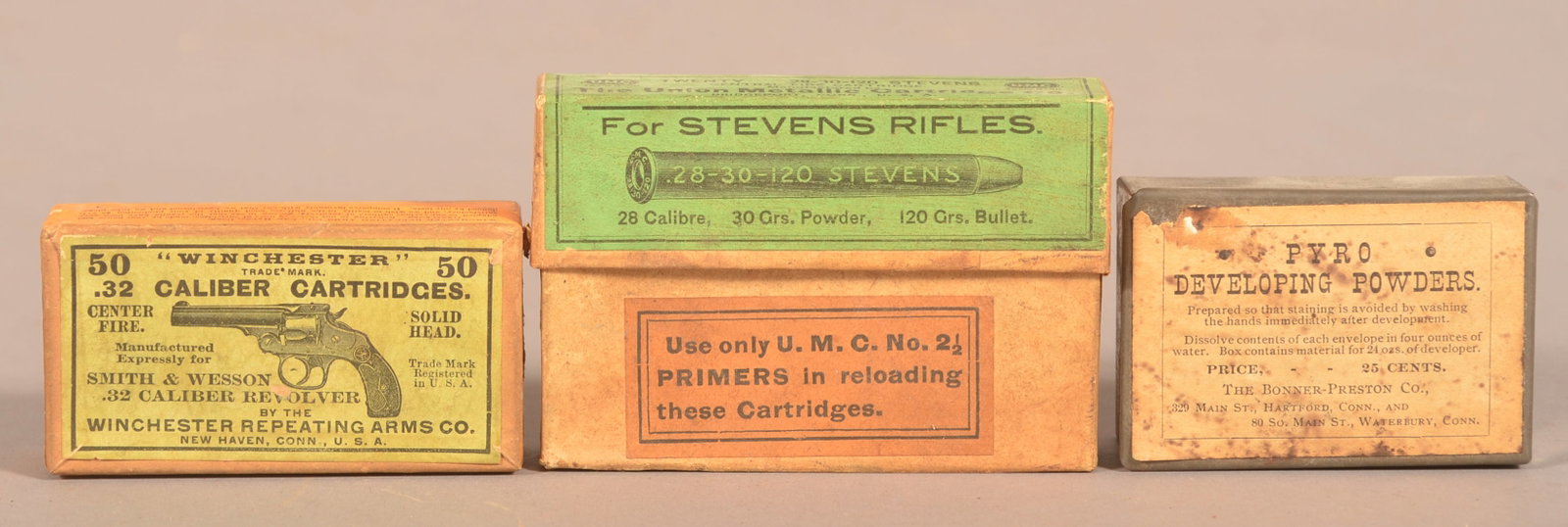 Group of Winchester and Stevens Cartridge Boxes.: Winchester .32 cartridge box with some unfired rounds still inside. Stevens U.M.C. .28 rifle cartridge box is empty. Also included is a "Pyro Developing Powders" tin with paper label. Together they me
