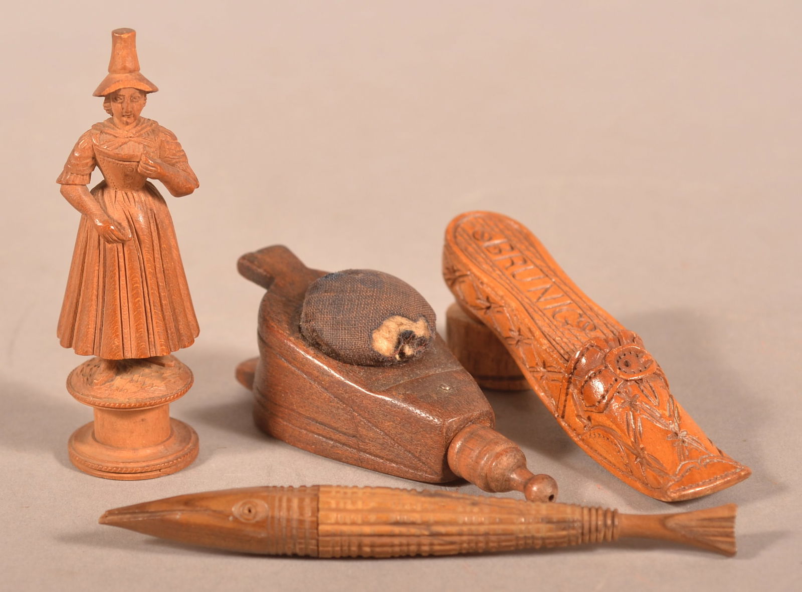 Four Folk Art Carved Wood Sewing Accessories.: All are 19th century, including a woman spool holder and three needle cases; fish, shoe and bellows (also a pin cushion). Fish, 4-1/2'l.