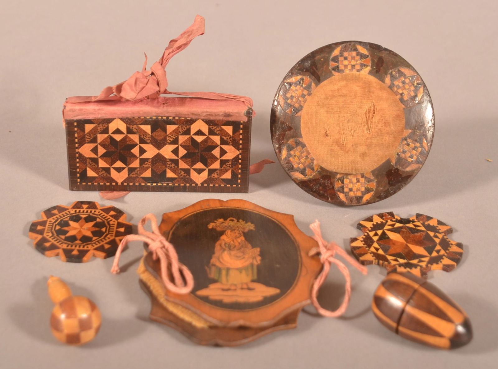 Lot of Tunbridge Ware/Inlaid Sewing Accessories.: Circa 1840. Including a pin cushion clamp, needle cases, thread winders, miniature darner and an egg-shape thimble case with thimble. Pin cushion, 3-1/2"h. x 2-7/8" diam.
