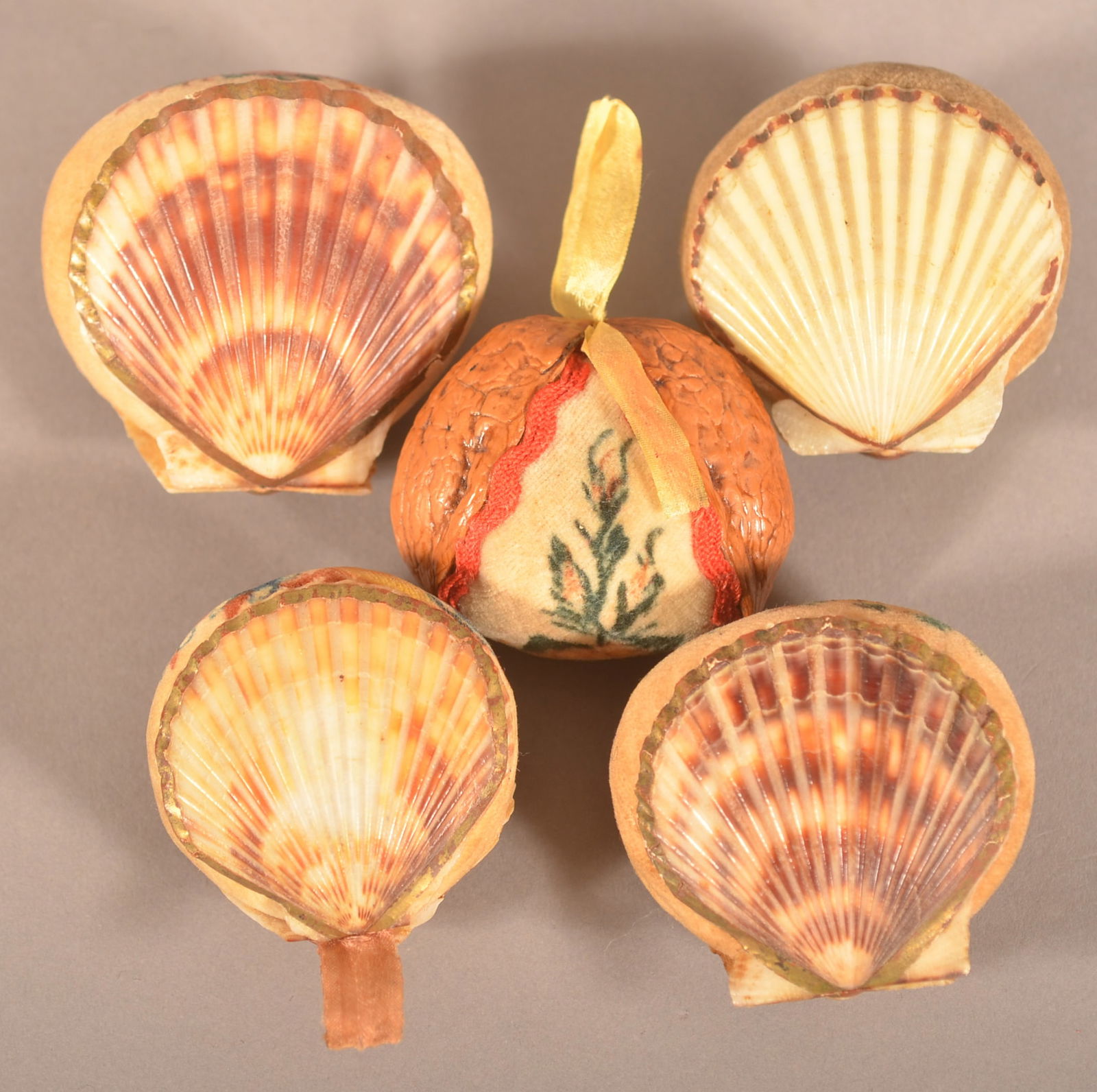 Five Antique Theorem-Painted Pin Cushions: Four are scallop shells and one is a rare walnut shell. Largest, 2" square.
