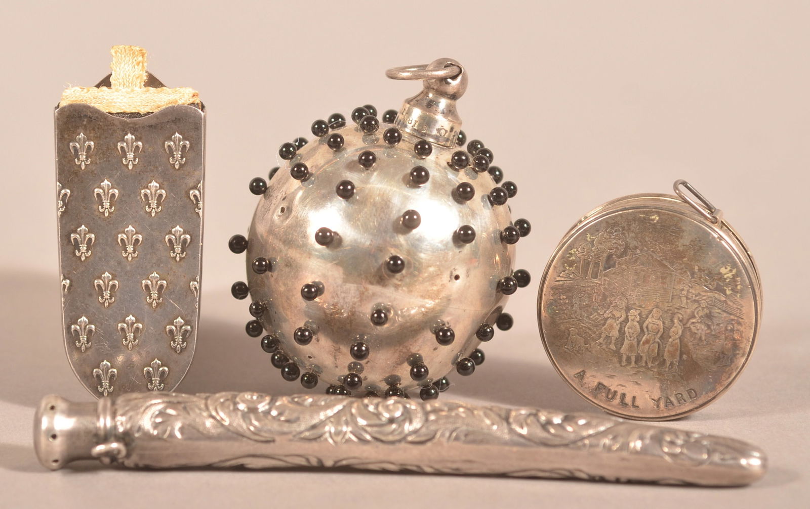 Four Antique Sterling Sewing Accessories.: Including a ball-form pin cushion, two various needle cases and a tape measure. Largest needle case, 4-3/4"l.