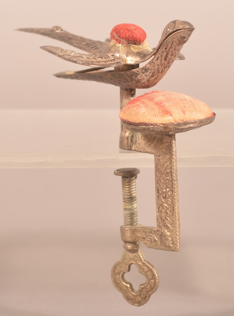 Waterman Silver-Plated Sewing Bird Pin Cushion.: Original plated metal with embossed floral and foliate designs. C-clamp with double pin cushions, wings stamped "PATENTED" and "FEB. 15, 1853". 5"h. x 2"w. x 3-3/4"l.
