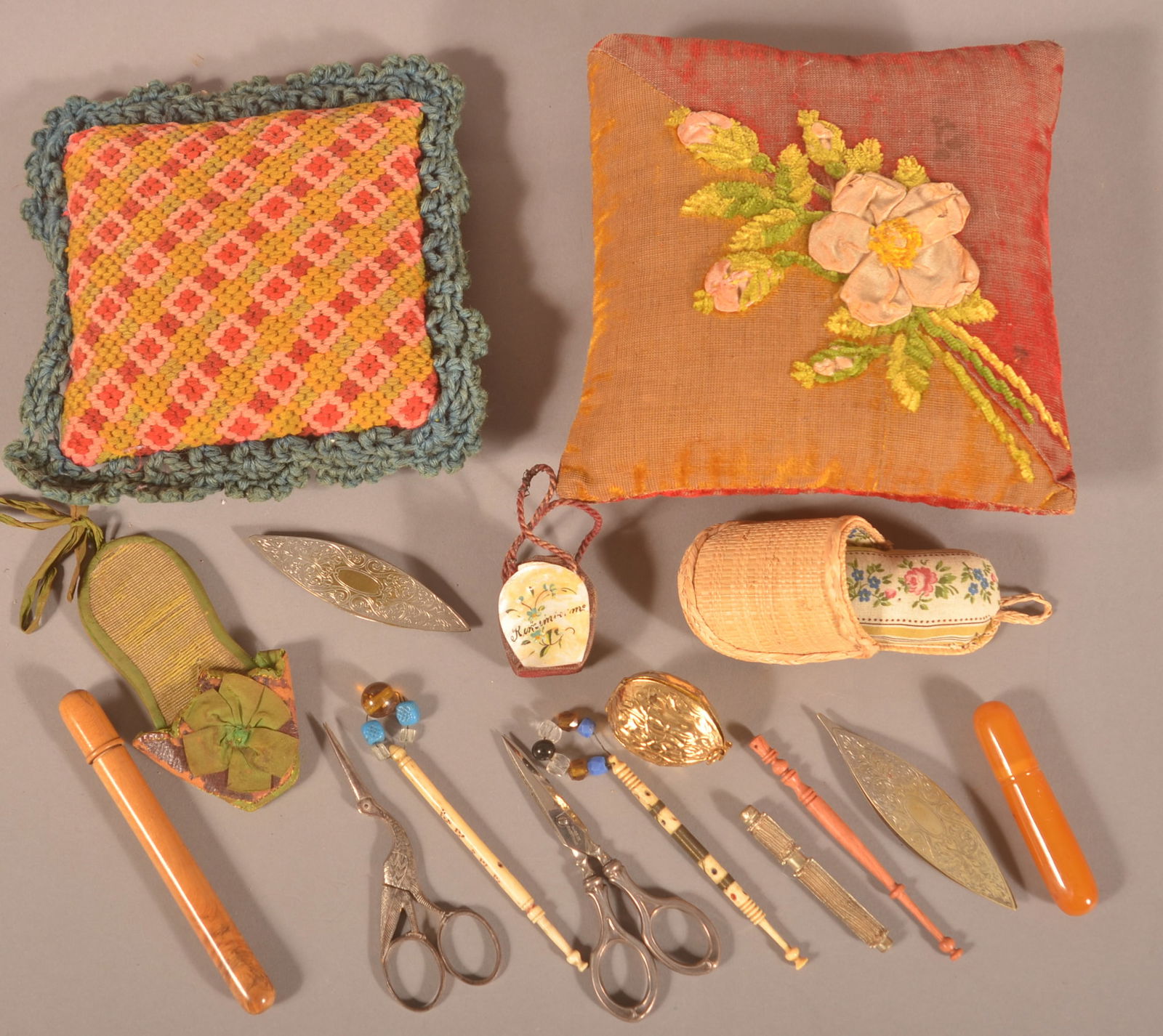 Lot of Antique Sewing-Related Items.: Including pillow pin cushions, scissors, thread winders, bone lace bobbins, silver-plate tatting shuttles, needle cases and thimble cases with thimbles. Largest pin cushion, 6-1/2" square.
