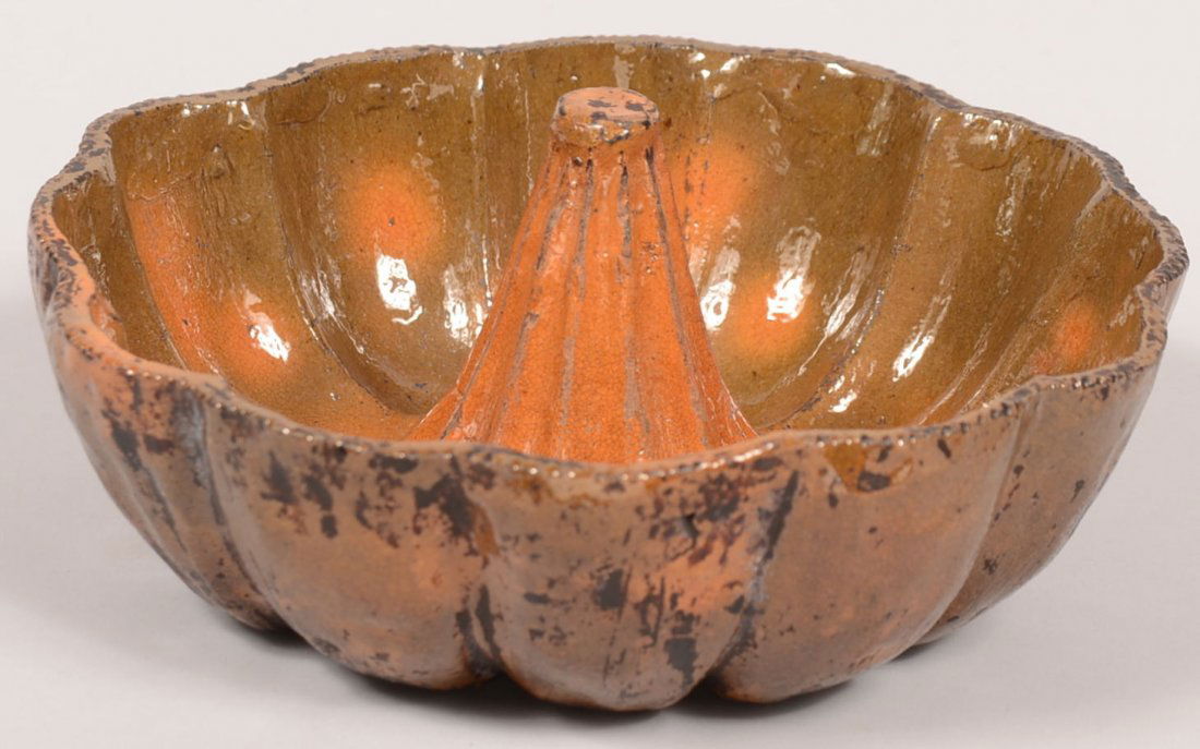 29. 19th Century Redware Pottery Turk's Head Food Mold.: 29. 19th Century Redware Pottery Turk's Head Food Mold. Scalloped coggle wheel edge and ribbed center post with orange and green glaze. 3 1/4"h x 8 3/4"dia. Condition: Good with minor wear.