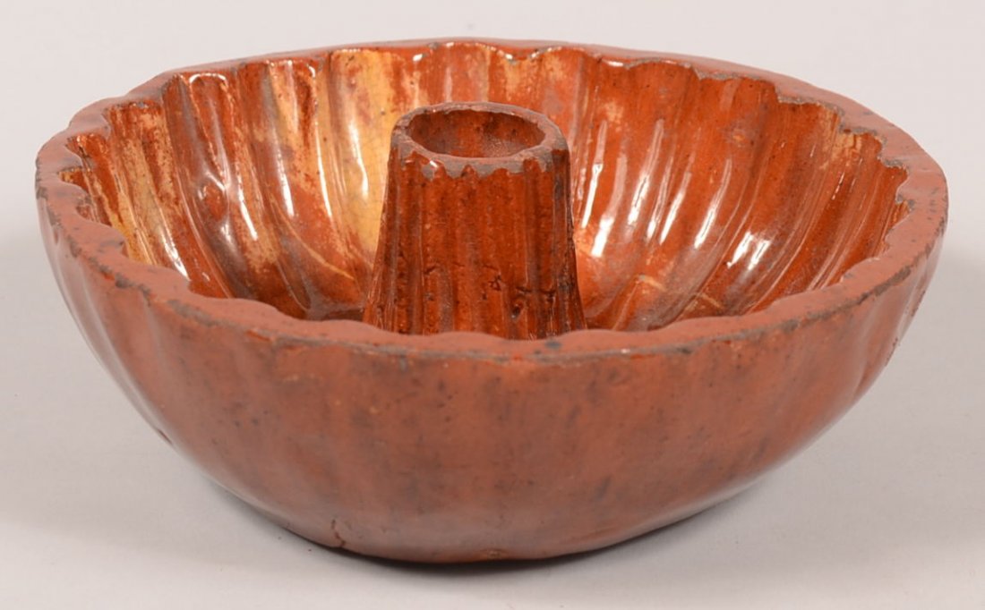 46. 19th Century Redware Pottery Turk's Head Food Mold.: 46. 19th Century Redware Pottery Turk's Head Food Mold. Round form with interior scalloped edge and ribbed center post with yellow orange and brown mottled glaze. 2 1/4"h x 6 1/4"dia. Condition: Good