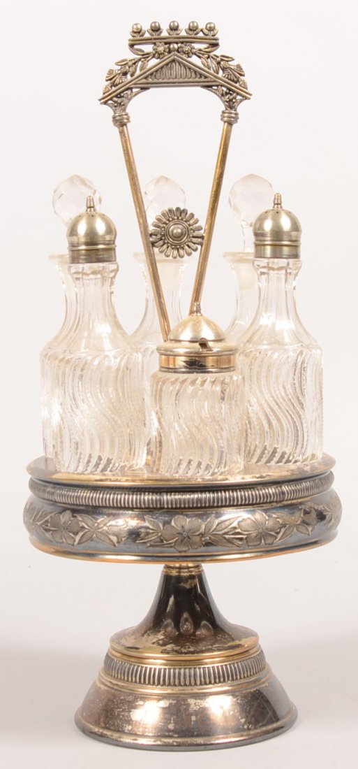 104. Victorian Silverplate Castor Set. Floral designs a: 104. Victorian Silverplate Castor Set. Floral designs and carousel pedestal base, complete with six swirl pattern glass castor bottles. 16 1/2" high. Condition: Bottles are very good, Silverplate show