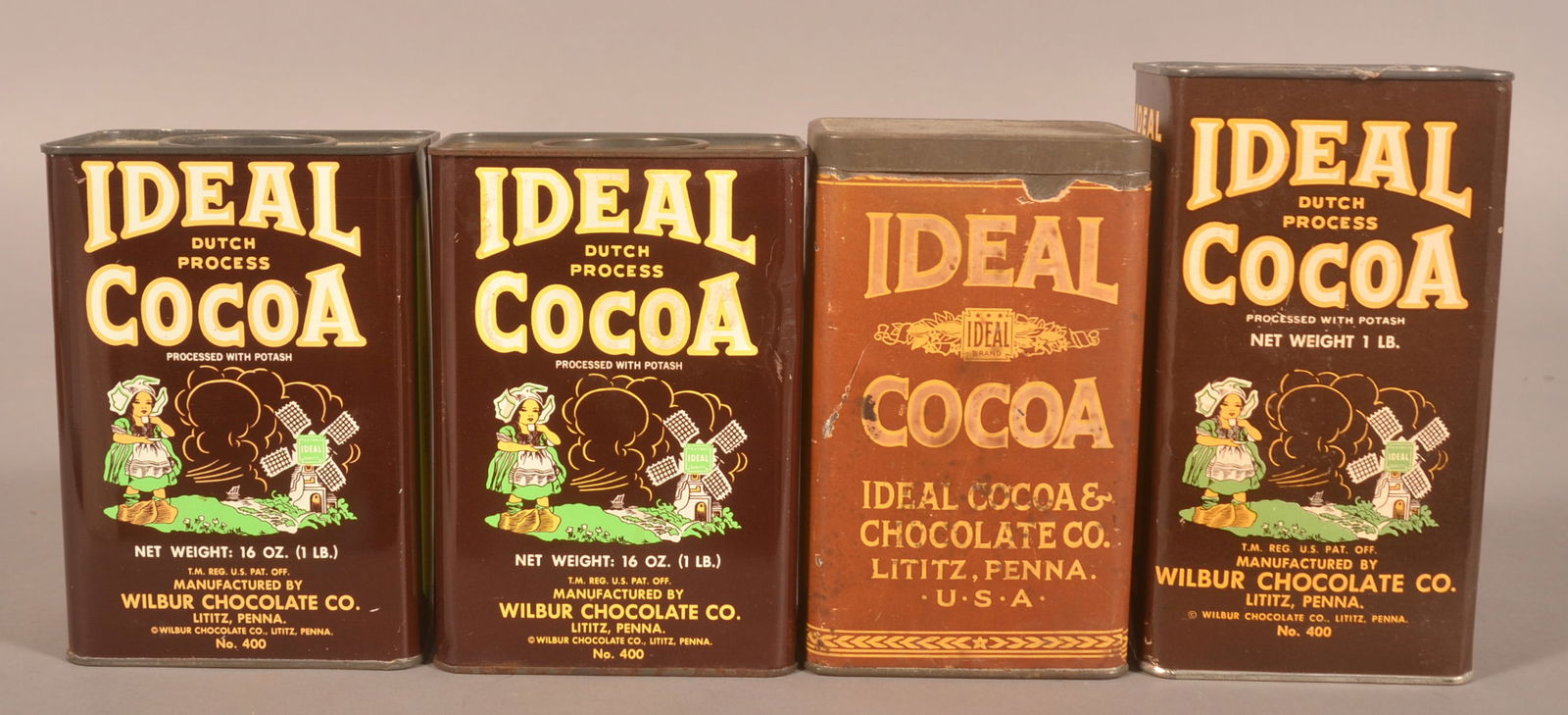 Collection of Ideal 1 lb. Cocoa Tins.: Four tins total, including early paper label-over-tin, two tins and one cardboard body tin. Provenance: James Hoffman Collection. Tallest, 6-5/8"H x 3-3/4"W x 2-1/2"D