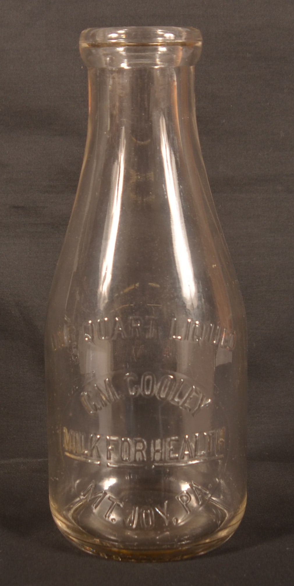 C.M. Cooley 1-Quart Mt Joy, PA Milk Bottle.: Maker's mark and mold number on bottom glass. Bottle is clear and shows very well. Provenance: James Hoffman Collection. 9-1/2"H