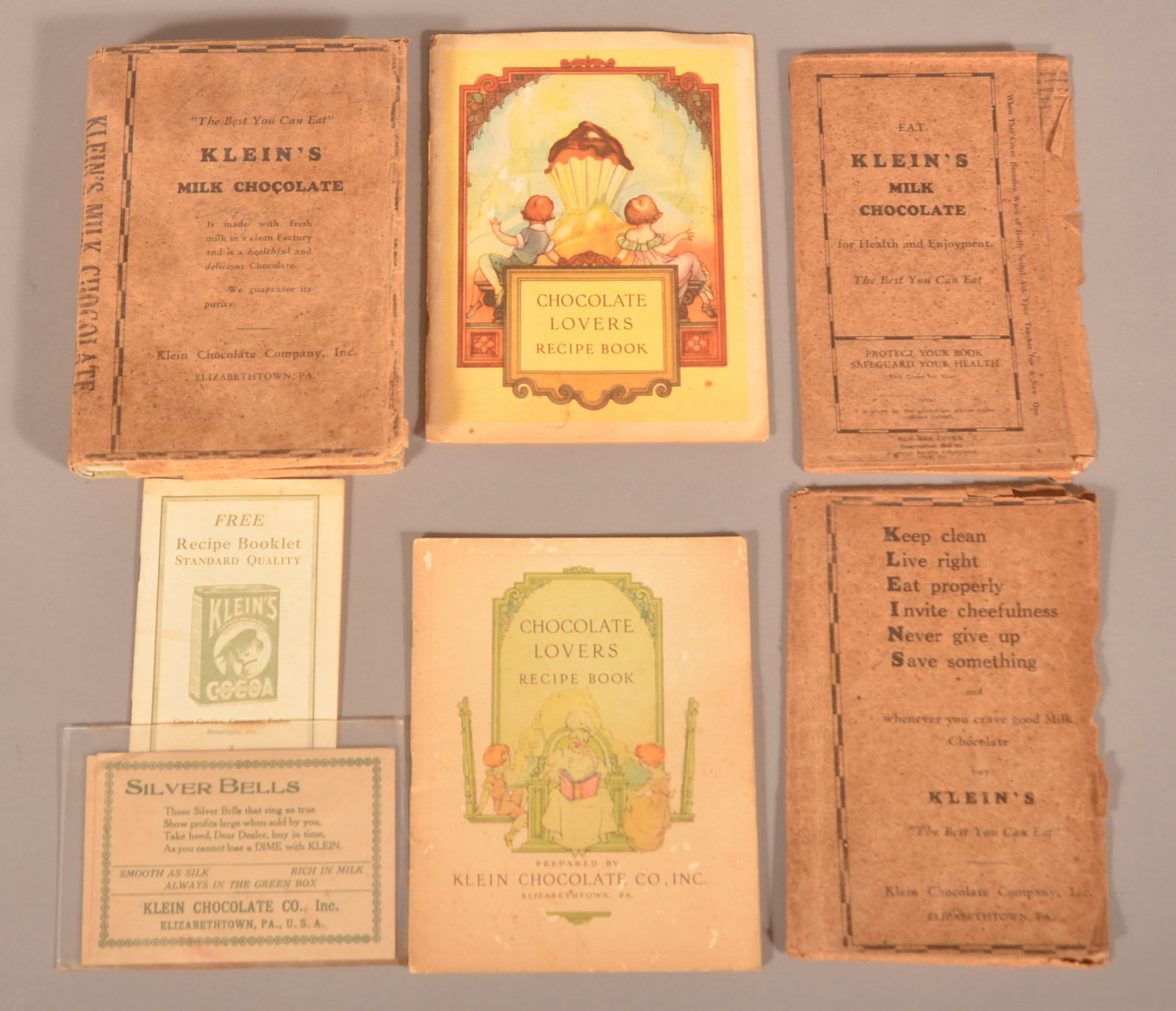 Klein's Chocolate Recipe Booklets & Ephemera.: Three recipe booklets, one featuring the parrot logo, two paper premiums featuring the silver bells, and two paper book covers with advertising. Provenance: James Hoffman Collection. Largest recipe bo