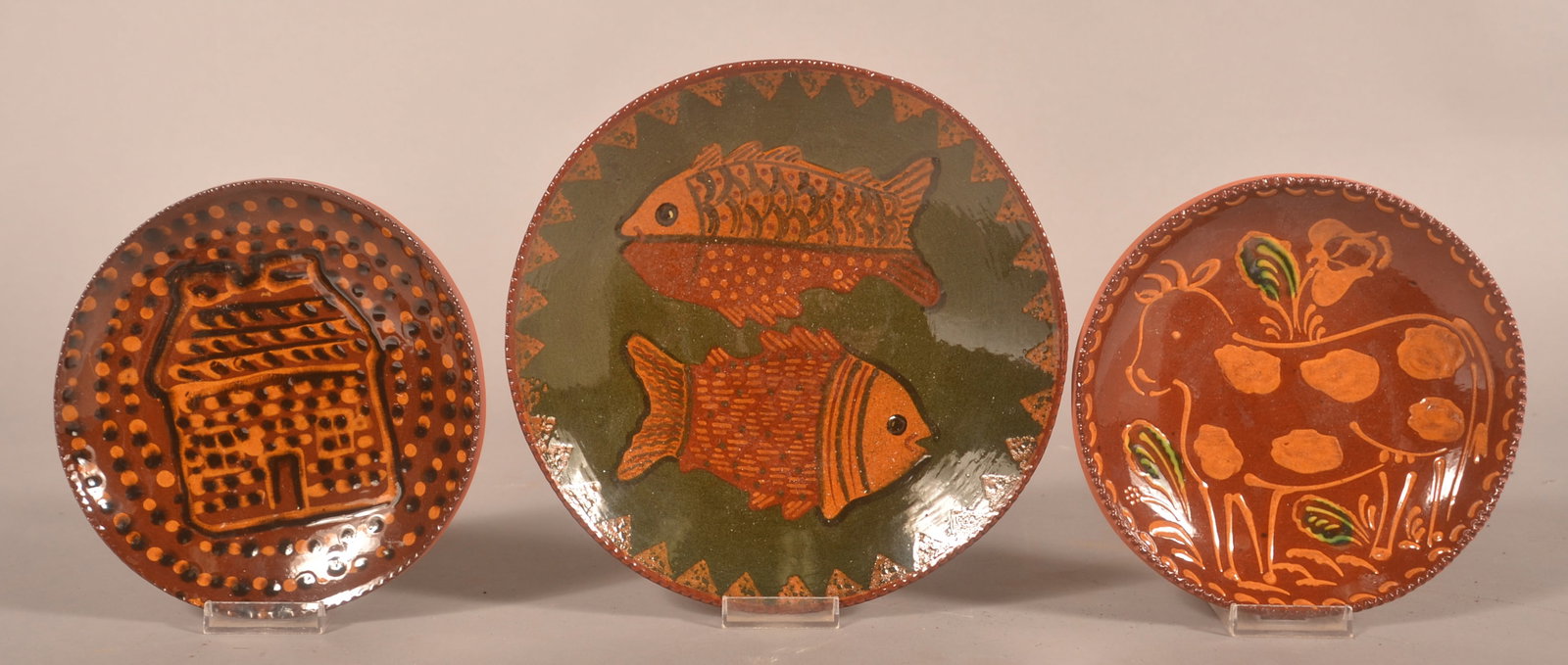 3 Ned Foltz Redware Plates: Each signed and dated on the reverse, depicting a log house, spotted cow and two fish. (2) 7 1/2"D, (1) 9 1/2"D