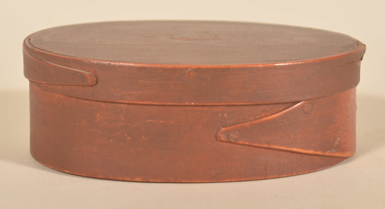 Small Early Oval Copper Nail Pantry Box: Plane marks still visible on lid. Wonderful blood red surface with Shaker-style bands secured with copper nails. 1825-1840. 1 5/8"H x 5"W x 3 5/8"D