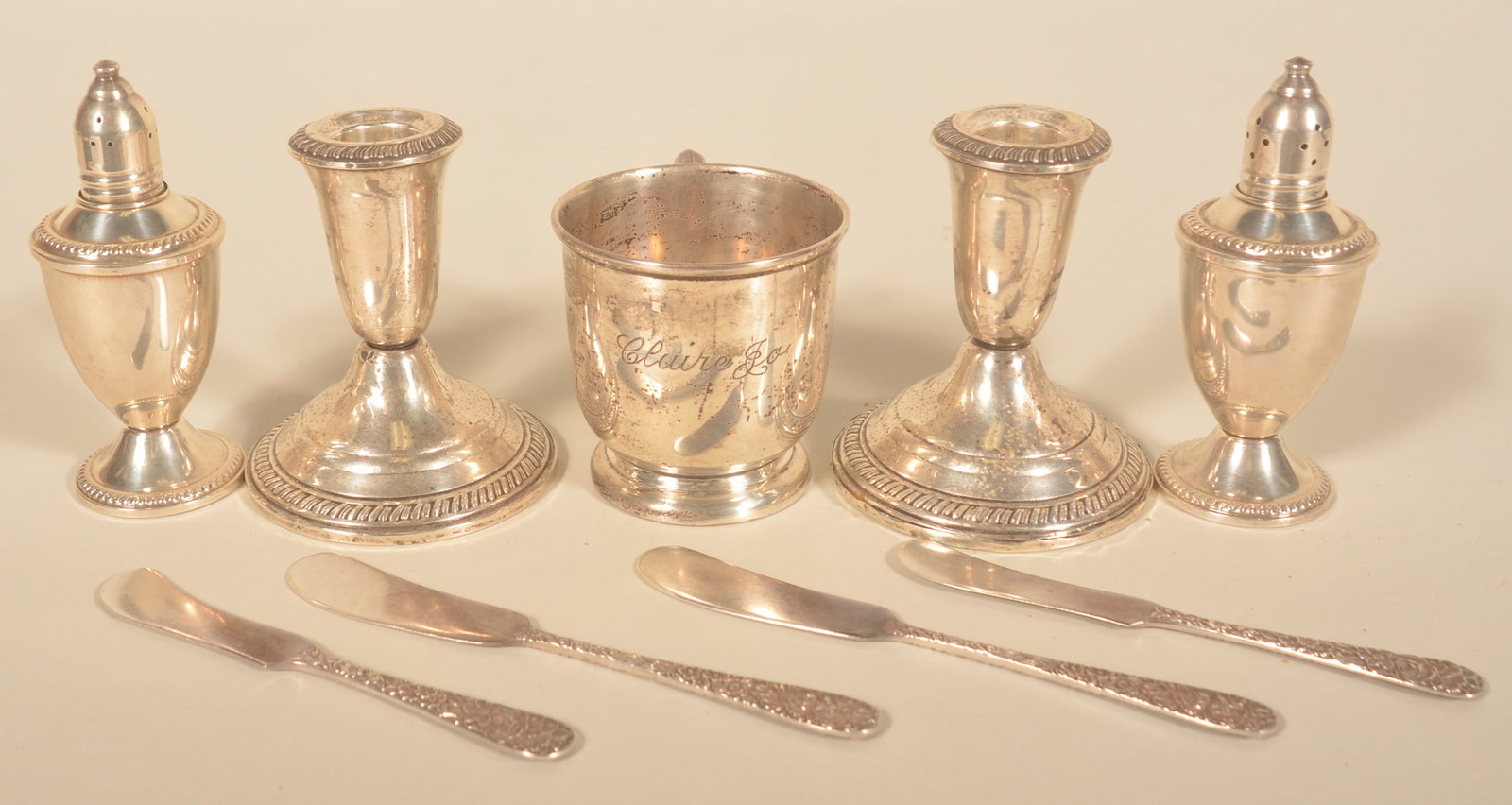 Group of 9 Sterling Silver Pieces: 4 S. Kirk and Son butter knives. Weighted salt and pepper shakers marked Ouchin. Cup marked Preisner and 2 weighted candleholders marked Crown. 9 pieces total. Shakers, 4 1/2"H