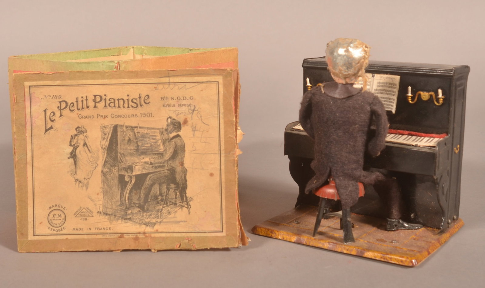 Boxed Martin 1901 Le Petit Pianiste Clockwork Toy: Rare toy complete with the original box in working condition. Seated man at the piano who moves his hands back and forth while his body sways. The song is "J'ai du bon tabac". Box, 5 1/2"H