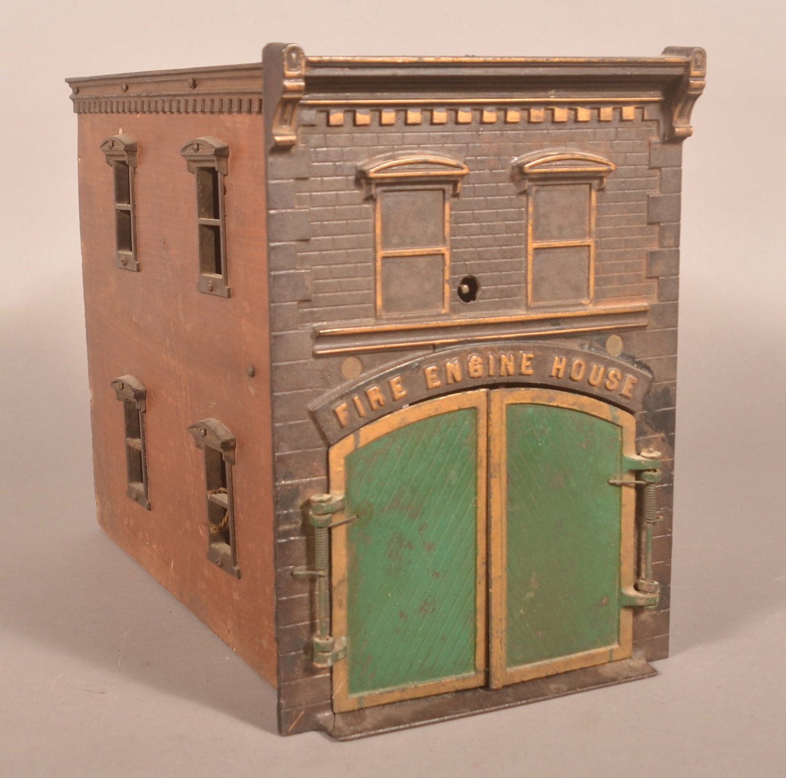 Antique Ives Clockwork Fire Engine House: Late 19th century. Wonderful details with original paint to the cast iron and original finish to the wood sides. With key. 12"H x 8 1/2"W x 15 1/4"D