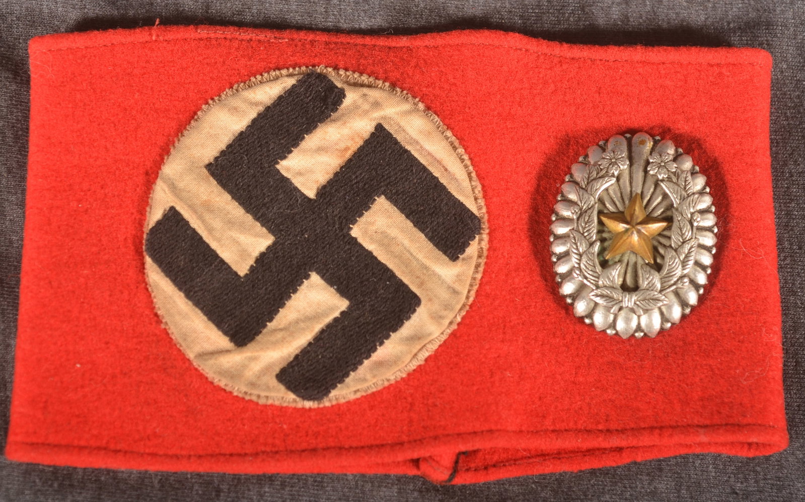 WWII German & Japanese Insignia: German armband brought home by a local veteran. Japanese officer insignia recovered by Lt. Col. Rex Anderson, street on Corregidor, Philippines. Provenance: The collection of Craig and Cynthia Wertz.