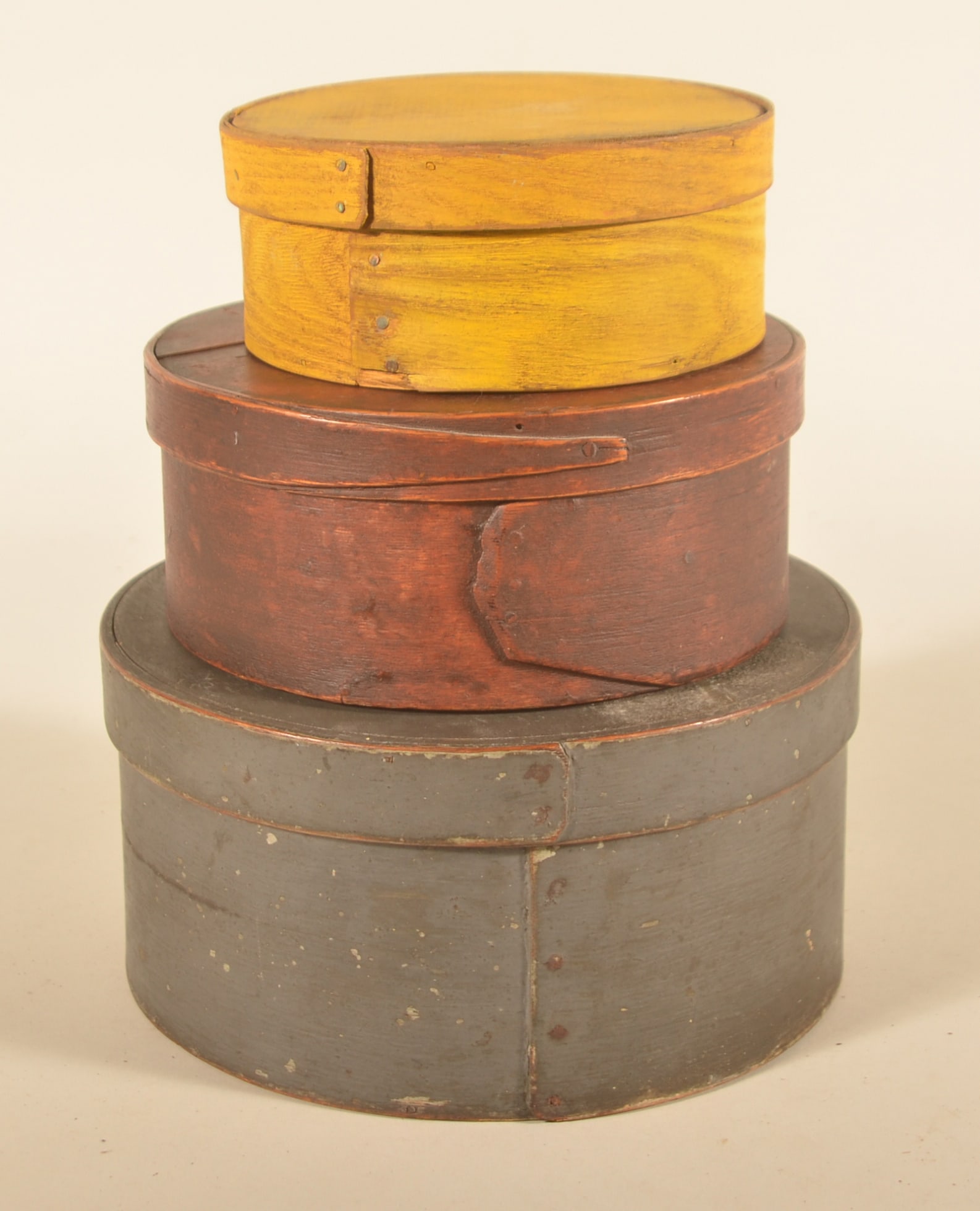 Graduated Stack of Painted Pantry Boxes: Three 19th-century New England painted pantry boxes. Largest box in a slate gray paint over the original Windsor green. Middle box in the original ox blood red with overlapping bands and copper nails.