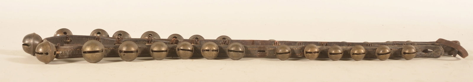 Set of Early Christmas Sleigh Bells: Three different size brass sleigh bells which are cotter pinned to the leather strap. The ends of the strap have a more crude way of closing which is original. Very nice example. Provenance: The colle