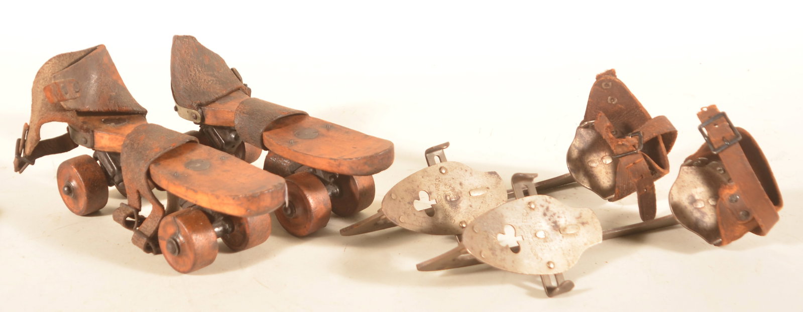 Antique Wood Roller Skates & Ice Skates: Pair of cast steel ice skates marked "Union Hardware Co." with leather straps. Pair of early wood, cast iron and leather roller skates. Provenance: The collection of Linda and the late Ed Althouse.