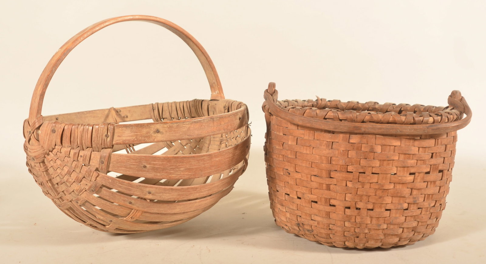 Antique Potato & Swing Handle Oak Baskets: Two baskets including a heavy duty oak potato basket with distinctive form and shape, early 20th century. Together with a splint ash with carved oak swing handle in a very nice worn patina. Potato bas