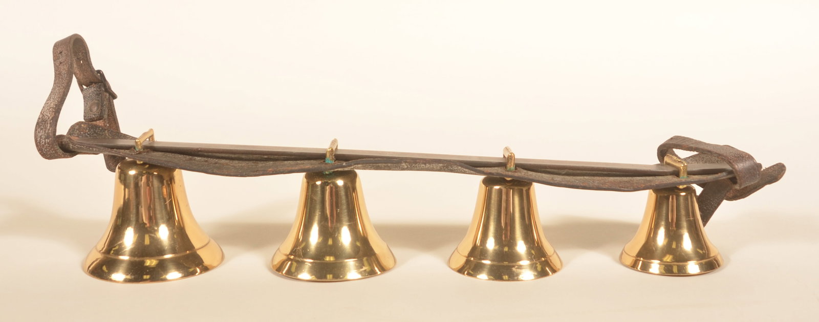Graduated Antique Christmas Sleigh Bells: Beautiful graduated set of 4 sleigh bells on the leather strap with buckles at both ends and a wrought iron strap across the top. For use on the shaft of the sleigh. 19"L