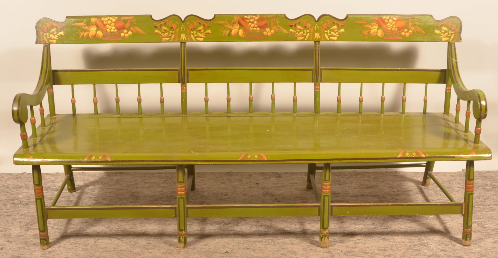 Half-Spindle-Back Pennsylvania Settle Bench: Single-board seat, shaped crest, scrolled arms, stretcher base with turned legs. Ca. 1840-1850. Later green paint with painted baskets of fruit and floral decoration. 34 1/2"H x 74 1/2"W x 21 1/2"D