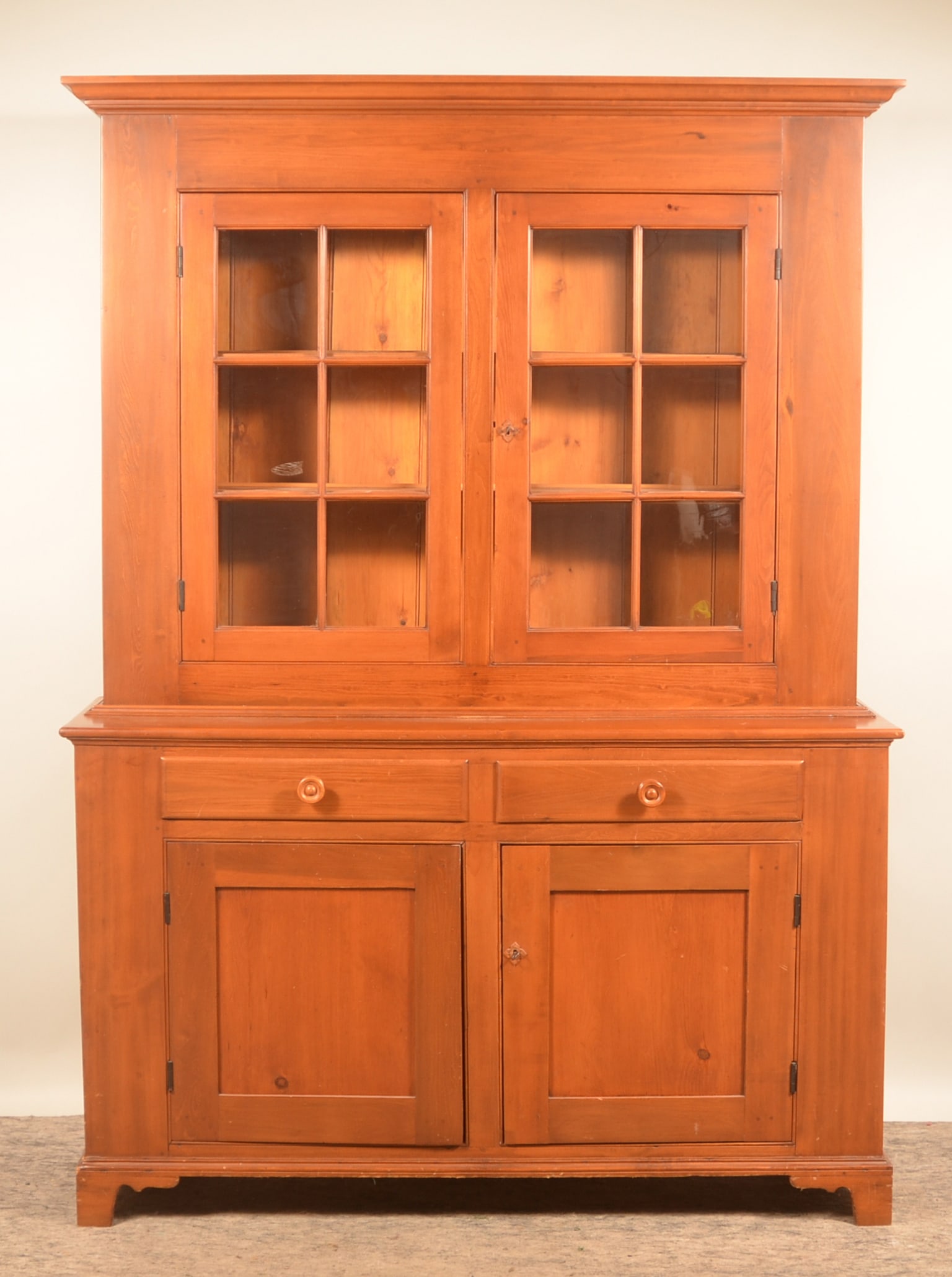 12-Pane Pennsylvania Step-Back Dutch Cupboard: 2-piece pine step-back cupboard with bracket feet, two doors with six panes of glass each, two dovetailed drawers over two recessed-panel doors in the base. 80 1/2"H x 61 1/2"W x 19 1/4"D