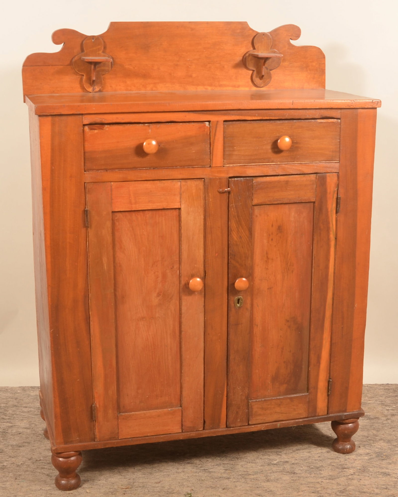 Pennsylvania Country Jelly Cupboard: Shaped splashback with candle holders, two dovetailed drawers over two recessed-panel doors, and turned feet. Provenance: The collection of Linda and the late Ed Althouse. 57"H x 41 1/2"W x 18 1/4"D