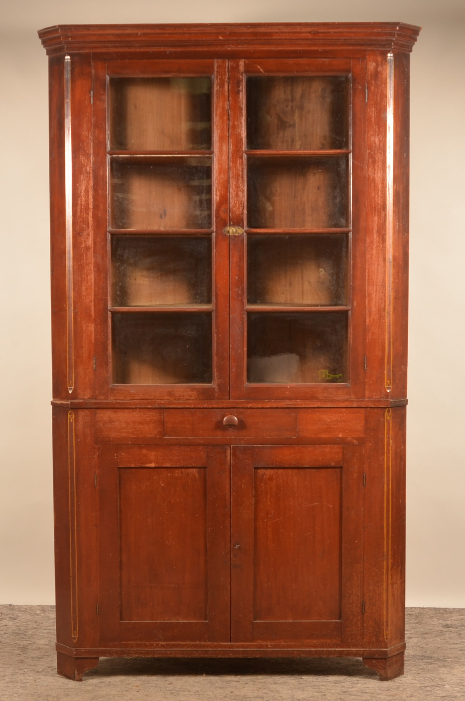 8-Pane 19th C. West Virginia Corner Cupboard: 2-piece cupboard in a worn red wash with mustard highlights on the chamfered edges and two 4-pane doors. Ca. 1860-1880. Dovetailed drawer with original wood knob, recessed paneled doors with lock and